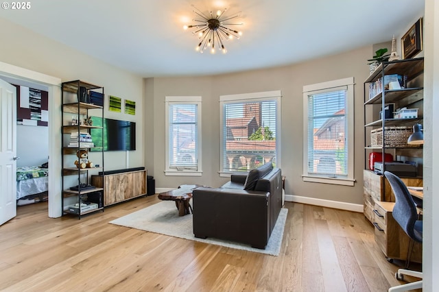 living area featuring baseboards, a chandelier, and light wood-type flooring