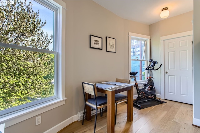 workout room featuring baseboards and light wood-style flooring