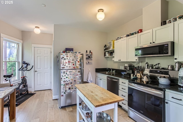 kitchen featuring butcher block countertops, appliances with stainless steel finishes, a sink, and open shelves
