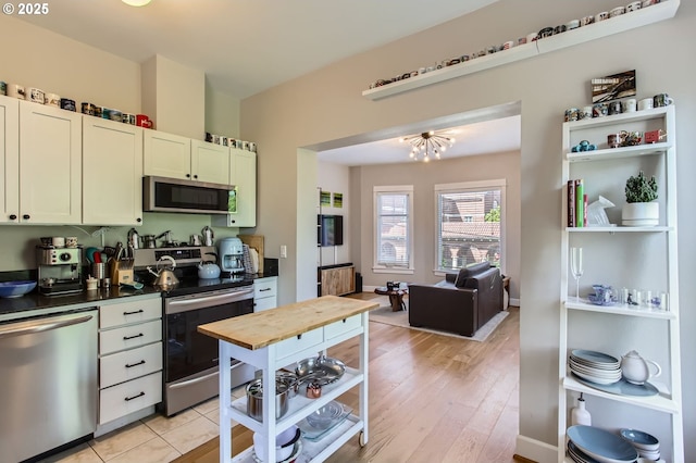 kitchen with light wood-style floors, appliances with stainless steel finishes, white cabinetry, and open floor plan