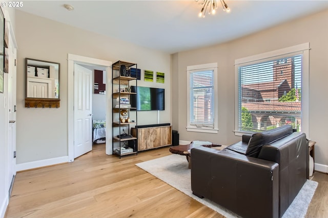 living room with baseboards, light wood-type flooring, and a notable chandelier