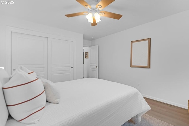 bedroom featuring wood finished floors, ceiling fan, baseboards, and a closet