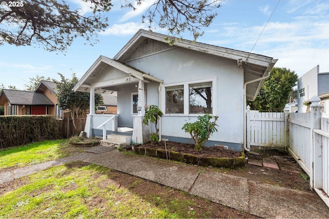 bungalow-style house featuring stucco siding and fence