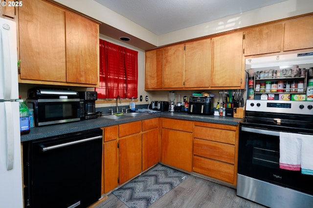 638 SE Polk St, Camas, WA 98607 - kitchen with stainless steel appliances, a sink, wood finished floors, and dark countertops