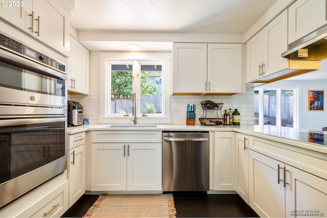 2022 Floral Hill Dr, Eugene, OR 97403 - kitchen with stainless steel double oven, a sink, white cabinets, tasteful backsplash, and dark stone counters
