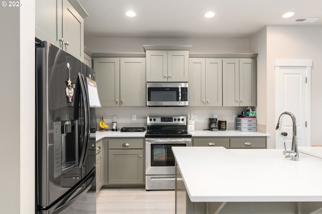 kitchen with gray cabinets, appliances with stainless steel finishes, light countertops, and recessed lighting