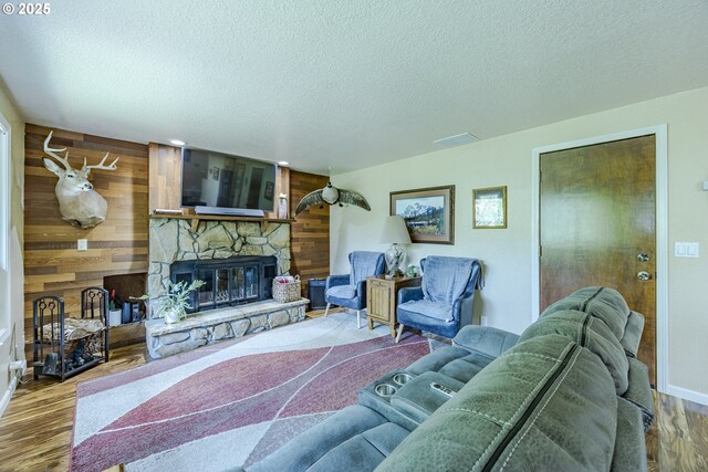 40211 Deerhorn Rd, Springfield, OR 97478 - living area featuring a fireplace, wood finished floors, a textured ceiling, wooden walls, and baseboards