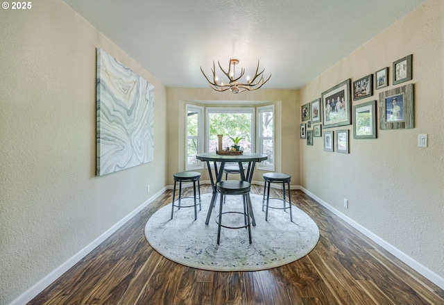 40211 Deerhorn Rd, Springfield, OR 97478 - dining room featuring a textured wall, a chandelier, dark wood-style flooring, and baseboards