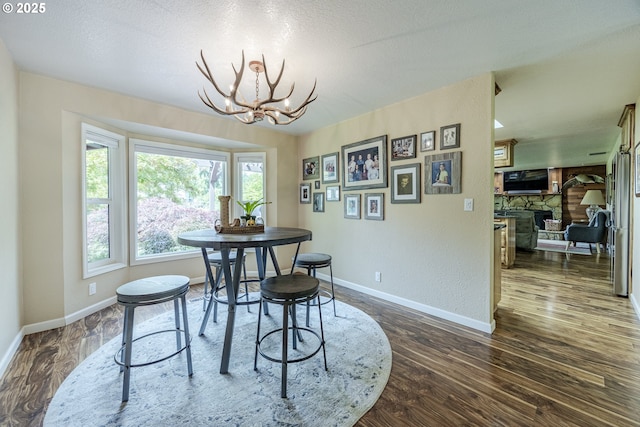 40211 Deerhorn Rd, Springfield, OR 97478 - dining area featuring a chandelier, dark wood finished floors, baseboards, and a textured ceiling