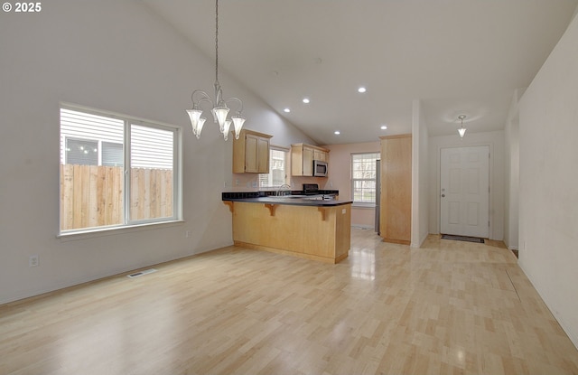 806 NW 15th Ave, Battle Ground, WA 98604 - kitchen with a peninsula, a breakfast bar, stainless steel microwave, dark countertops, and light wood-style flooring