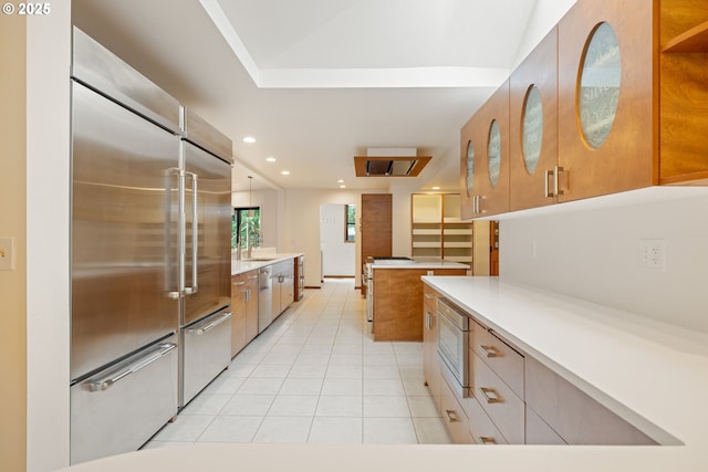 1940 SW 71st Ave, Portland, OR 97225 - kitchen with appliances with stainless steel finishes, light tile patterned floors, brown cabinetry, a sink, and light countertops