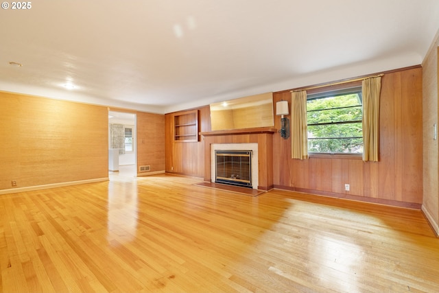 1940 SW 71st Ave, Portland, OR 97225 - unfurnished living room featuring light wood-style floors, a fireplace, healthy amount of natural light, and wooden walls