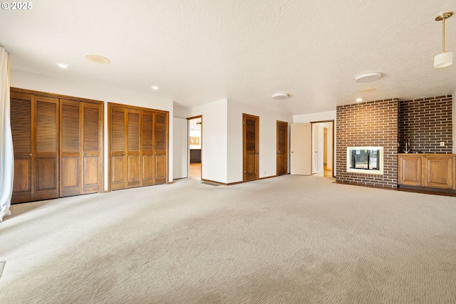 1940 SW 71st Ave, Portland, OR 97225 - unfurnished living room featuring light carpet, baseboards, a brick fireplace, a textured ceiling, and recessed lighting