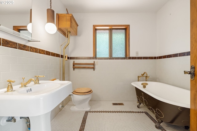1940 SW 71st Ave, Portland, OR 97225 - bathroom with tile walls, a freestanding bath, wainscoting, toilet, and tile patterned flooring