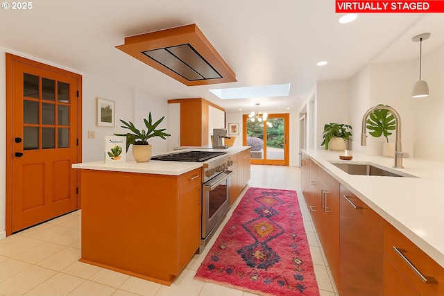 1940 SW 71st Ave, Portland, OR 97225 - kitchen with stainless steel range, light tile patterned floors, a sink, light countertops, and decorative light fixtures
