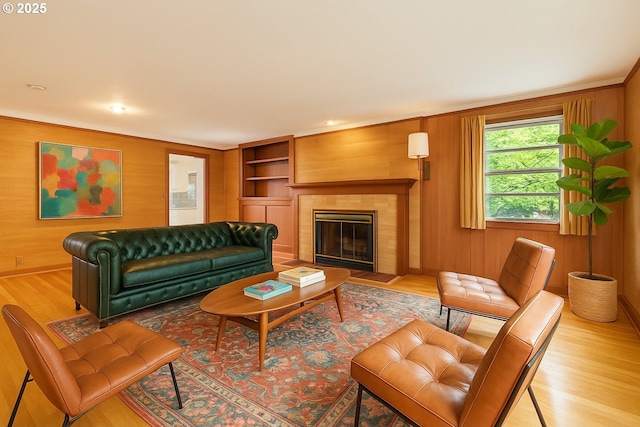 1940 SW 71st Ave, Portland, OR 97225 - living room featuring light wood-type flooring, a tiled fireplace, wooden walls, and crown molding