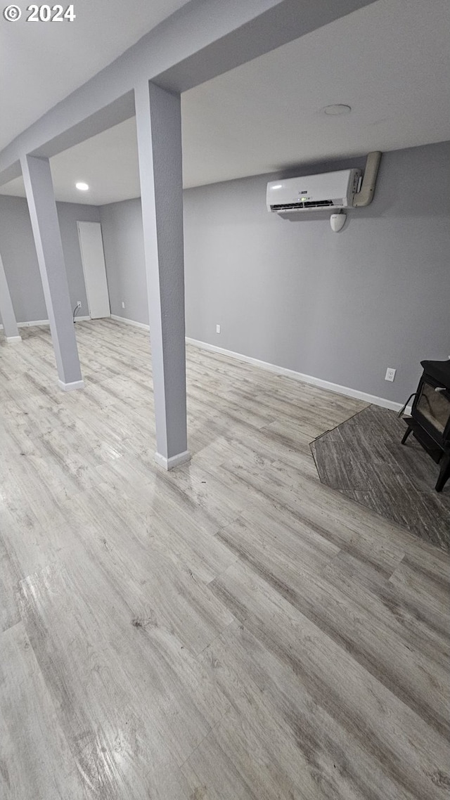 basement with light hardwood / wood-style floors and an AC wall unit