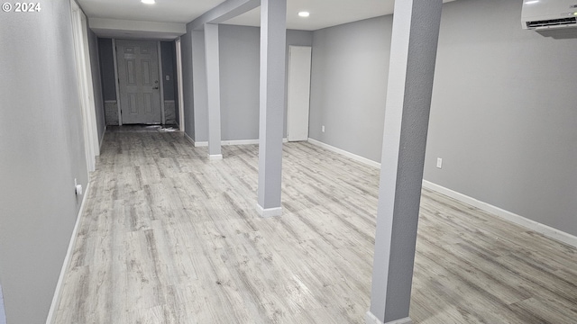 basement featuring light hardwood / wood-style floors and a wall unit AC