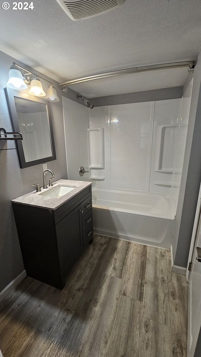 bathroom with shower / bathtub combination, a textured ceiling, hardwood / wood-style flooring, and vanity