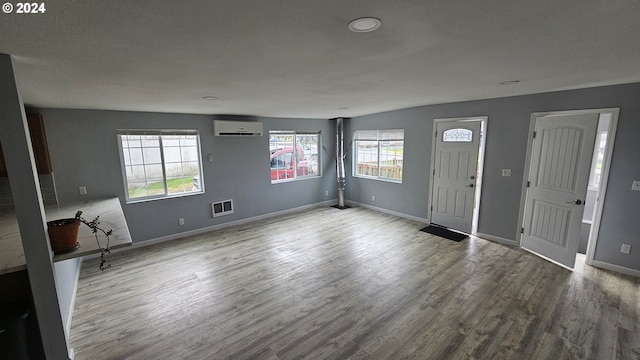 foyer entrance with an AC wall unit and hardwood / wood-style flooring