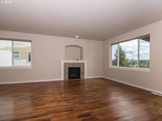 unfurnished living room with a premium fireplace, visible vents, wood finished floors, and baseboards