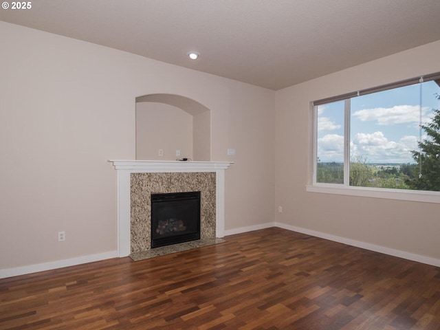unfurnished living room with baseboards, wood finished floors, and a high end fireplace