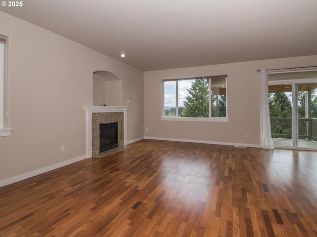 unfurnished living room with a premium fireplace, dark wood-style flooring, and baseboards