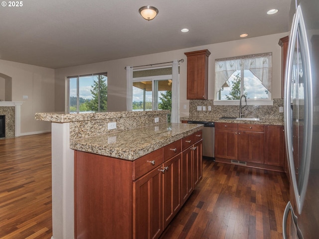 kitchen with a sink, appliances with stainless steel finishes, visible vents, a kitchen island, and dark wood finished floors