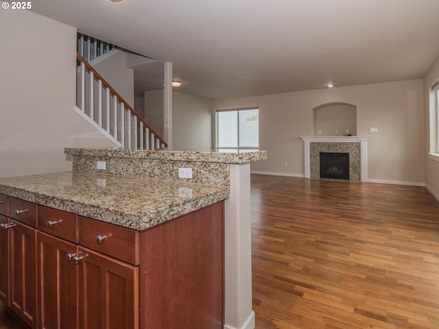 kitchen with light countertops, baseboards, open floor plan, a fireplace, and wood finished floors