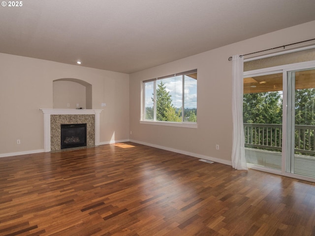 unfurnished living room featuring baseboards, recessed lighting, wood finished floors, and a premium fireplace