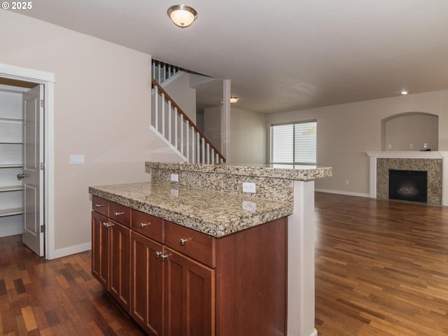 kitchen featuring light countertops, baseboards, open floor plan, dark wood finished floors, and a fireplace