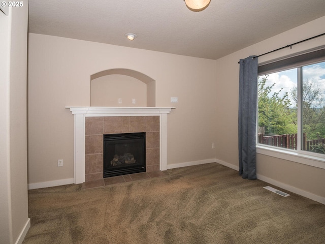 unfurnished living room with baseboards, visible vents, carpet floors, and a fireplace