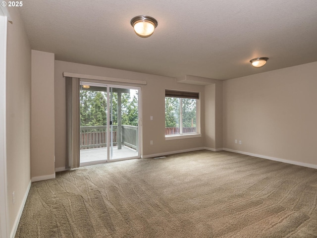 carpeted empty room featuring a textured ceiling and baseboards