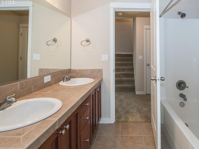 bathroom with double vanity, baseboards, tub / shower combination, and a sink