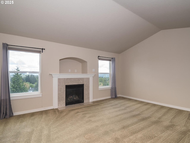 unfurnished living room with a tile fireplace, vaulted ceiling, and carpet floors
