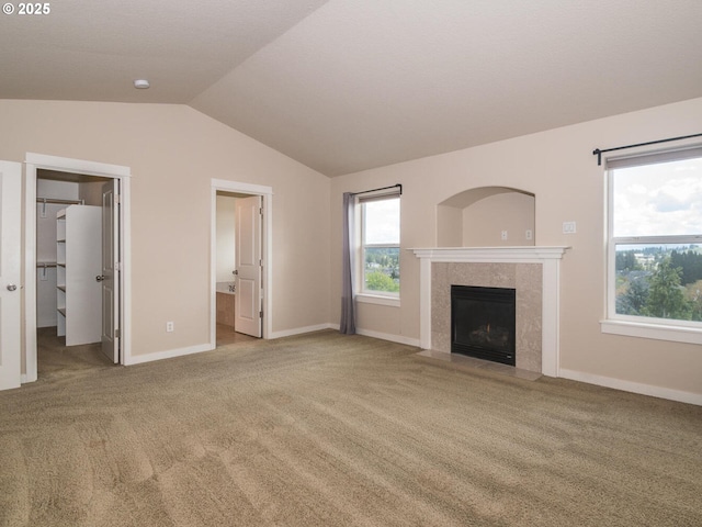 unfurnished living room with carpet, a wealth of natural light, vaulted ceiling, and baseboards
