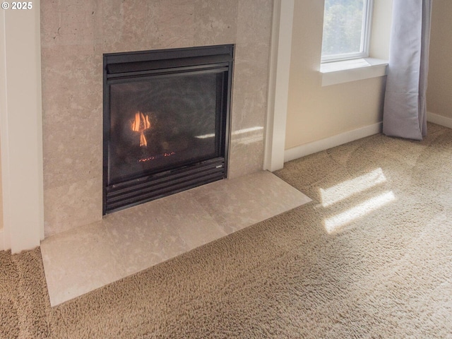 interior details featuring a fireplace with flush hearth, carpet flooring, and baseboards