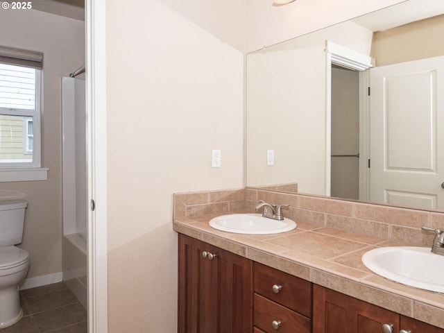 bathroom with double vanity, toilet, tile patterned flooring, and a sink