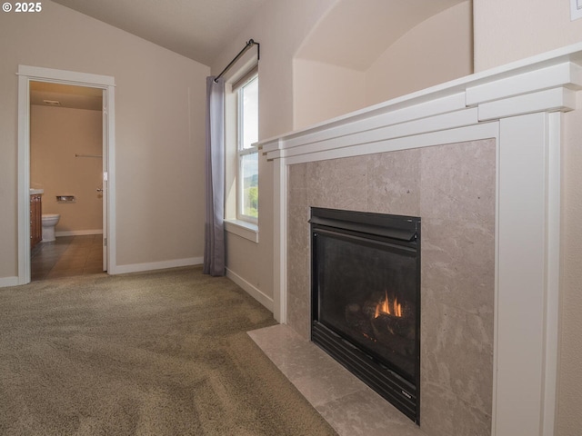 unfurnished living room featuring lofted ceiling, a tile fireplace, carpet, and baseboards