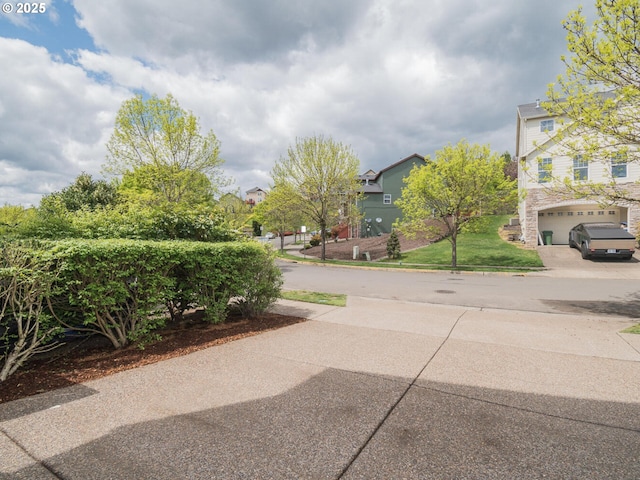 view of yard featuring a garage, a residential view, and driveway