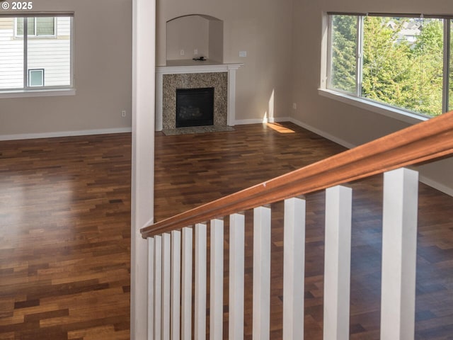 unfurnished living room featuring wood finished floors, a high end fireplace, and baseboards