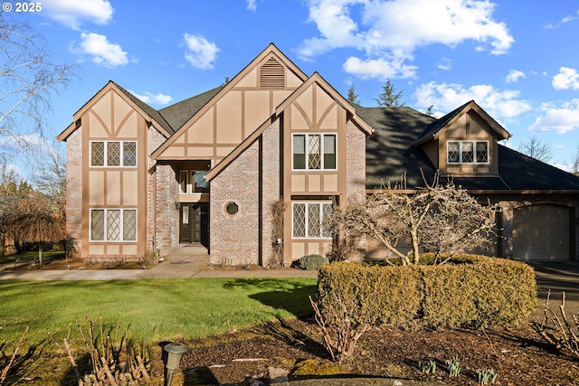 english style home featuring a garage and a front lawn