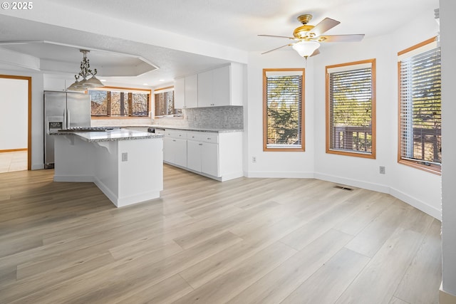 kitchen featuring a breakfast bar, white cabinets, a kitchen island, stainless steel fridge with ice dispenser, and decorative light fixtures