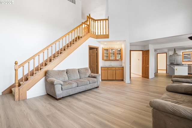 living room featuring a towering ceiling and light wood-type flooring