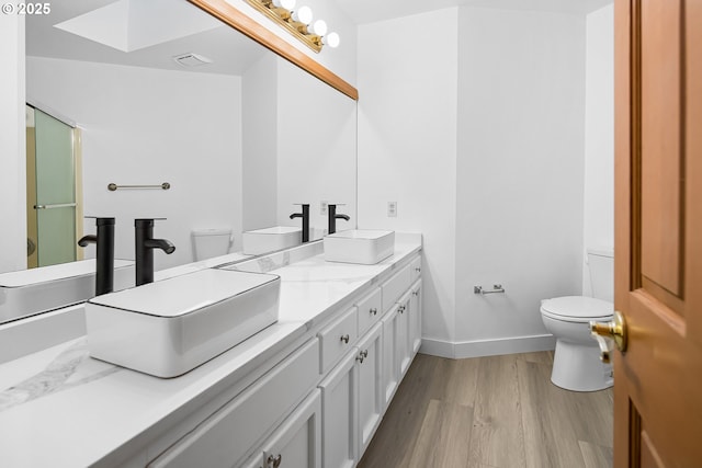 bathroom with vanity, a shower with shower door, hardwood / wood-style floors, and toilet