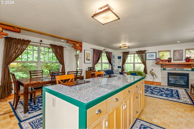 1650 Leatherwood Dr, Eugene, OR 97405 - kitchen featuring a fireplace, a kitchen island, tile countertops, a textured ceiling, and open floor plan