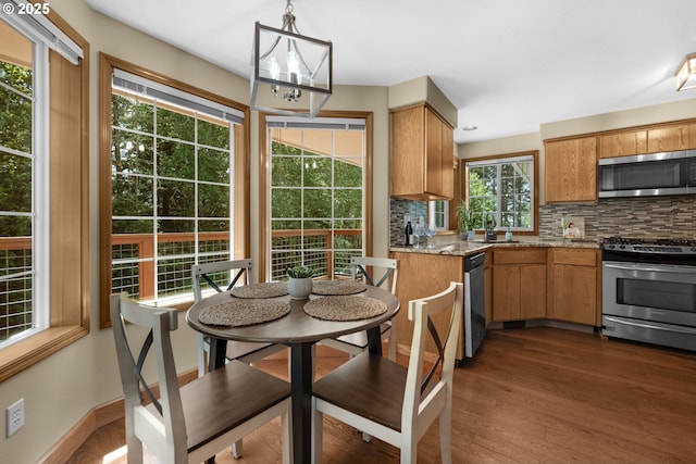 1820 Huckleberry Dr, Seaside, OR 97138 - kitchen with appliances with stainless steel finishes, decorative backsplash, dark wood-style flooring, and a chandelier