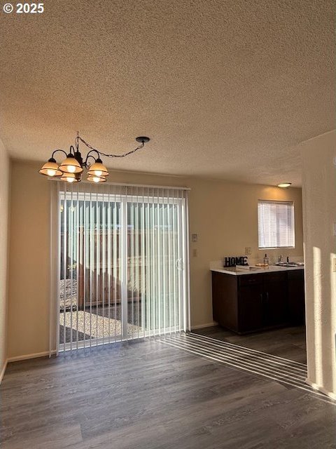 interior space with a textured ceiling, wood finished floors, and a notable chandelier