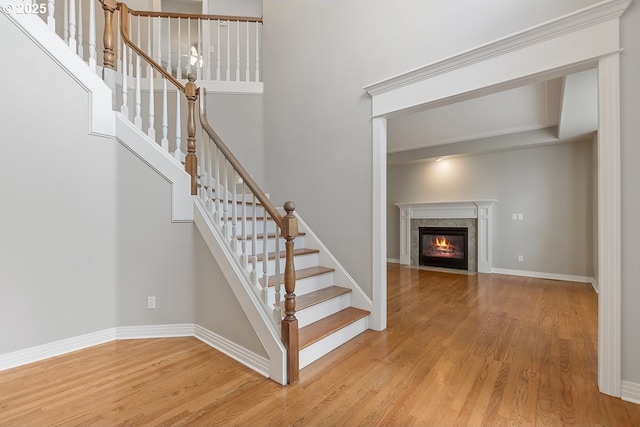 stairway with baseboards, wood finished floors, and a high end fireplace