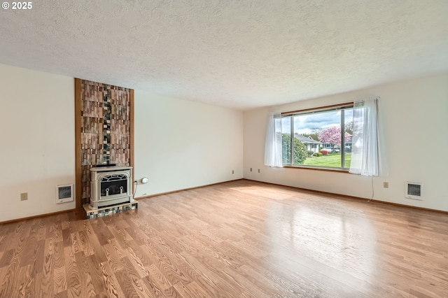 863 NE Fleming Ave Unit B-10, Gresham, OR 97030 - unfurnished living room featuring a textured ceiling, light wood-style flooring, a wood stove, heating unit, and baseboards